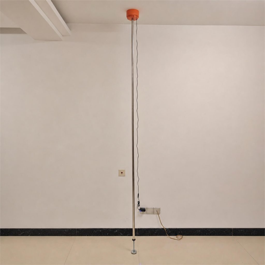 Ceiling Vibrator V2 installed vertically between the floor and ceiling with support rods and power cable